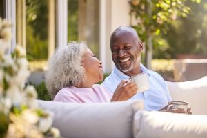 retirees | Retired Couple Sitting Outdoors At Home Having Morning Coffee Together