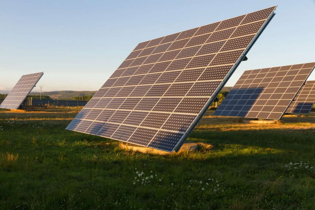 Plates or solar panels in the field, getting the last rays of the setting sun and hills with oak forests in the background