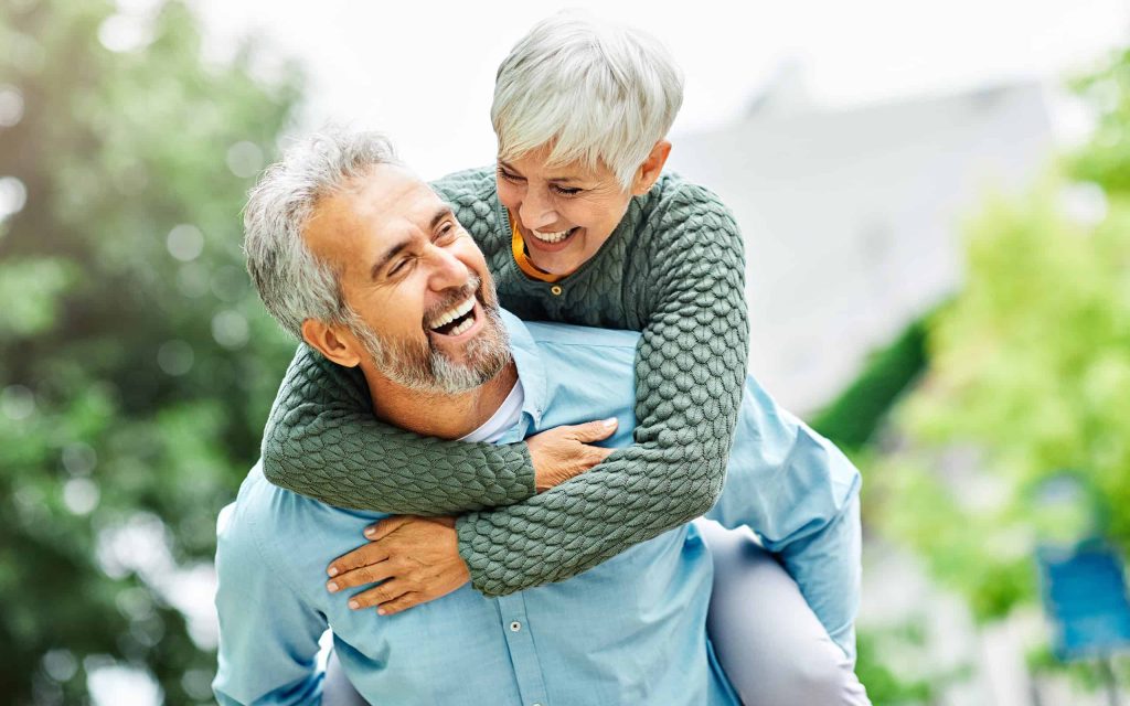 woman man outdoor senior couple happy lifestyle retirement together smiling love piggyback active mature