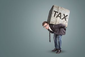 Businessman bending under a heavy stone with the word TAX printed on it