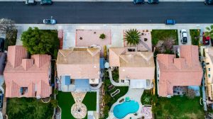 Above view of homes and neighborhoods in the Temecula and Murrieta California in Riverside county with pools, solar panels and tops of roofs with green trees and sun setting light.