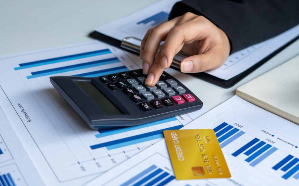 Businessmen use a calculator to calculate income and expenses in order to manage budgets to pay off credit card debt.