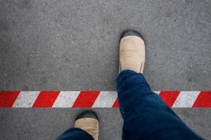 One walking across red and white line to prohibited area. Breaking the rule beyond the limit.