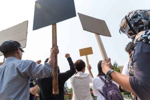 Men and women share a protest sign hold a megaphone. Mob concept, The youth crowd gathered to protest.