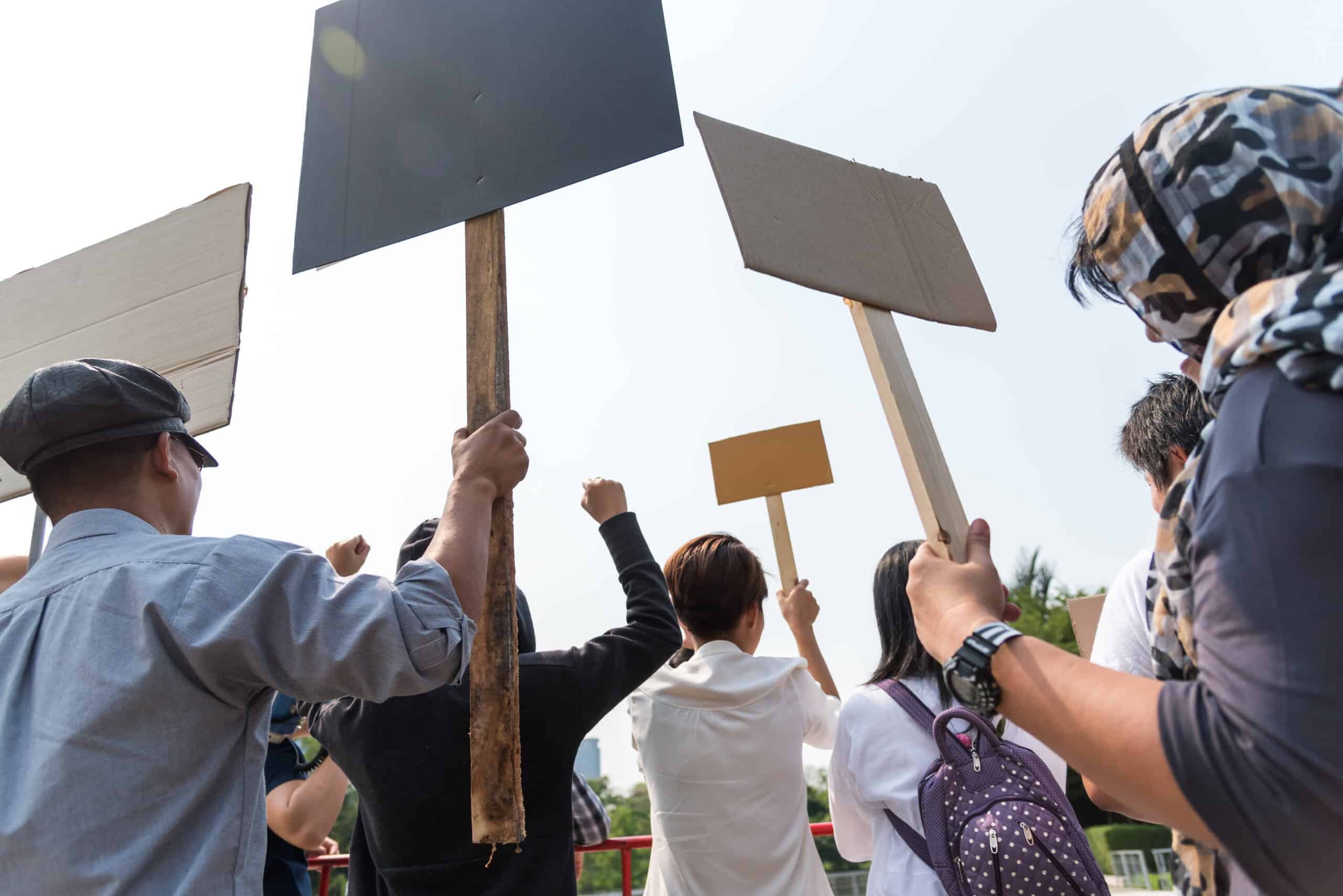 Men and women share a protest sign hold a megaphone. Mob concept, The youth crowd gathered to protest.