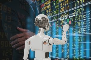 A humanoid robot with a white and gray body points its index finger towards a transparent, blue digital display filled with stock market data, including numbers, charts, and trading indicators. In the blurred background, the dark-suited upper body and arms of a human are visible. The overall scene suggests a blend of human oversight and advanced robotic technology in finance.