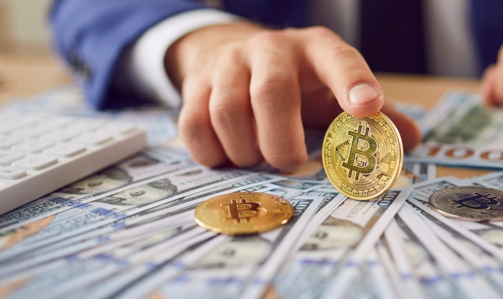 Close up of metal shiny bitcoin crypto currency coin on US dollar bills in hand of successful entrepreneur. Convenient payment in global economy market, savings, investment, trader buying, selling