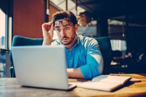 Shocked businessman getting off eyeglasses can't believe in low company income reading documents.Stressed entrepreneur doubting in receipt numbers worried about paying debt checking banking account