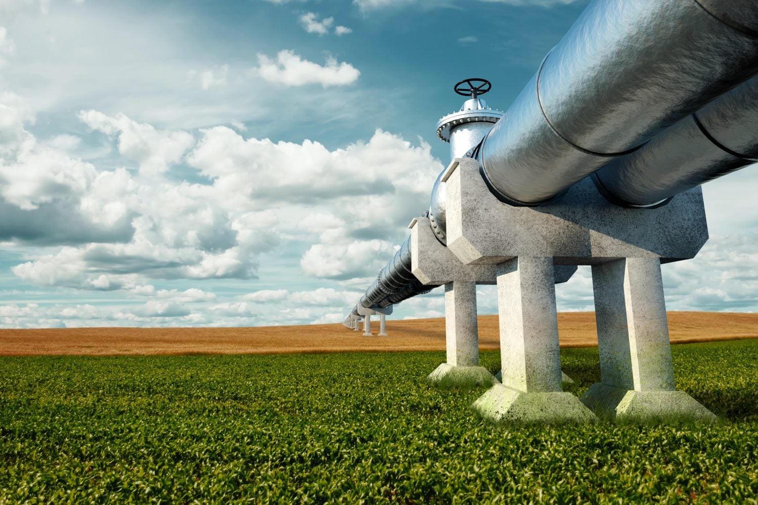 A large, silvery natural gas pipeline, supported by multiple concrete pillars, stretches across a rural landscape under a partly cloudy sky. The foreground shows a vibrant green field, which transitions into a golden-brown field further back.