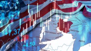 A composite image featuring the American flag rippling across the upper left. Overlaying the flag and a map of the Middle East are translucent financial candlestick charts with some bars in red (declines) and others in blue/white (gains), along with glowing blue and red numerical data points. The map prominently displays countries like Saudi Arabia, Iran (highlighted in red), Iraq, Syria, Egypt, and Afghanistan. The overall impression suggests global economic and geopolitical volatility.