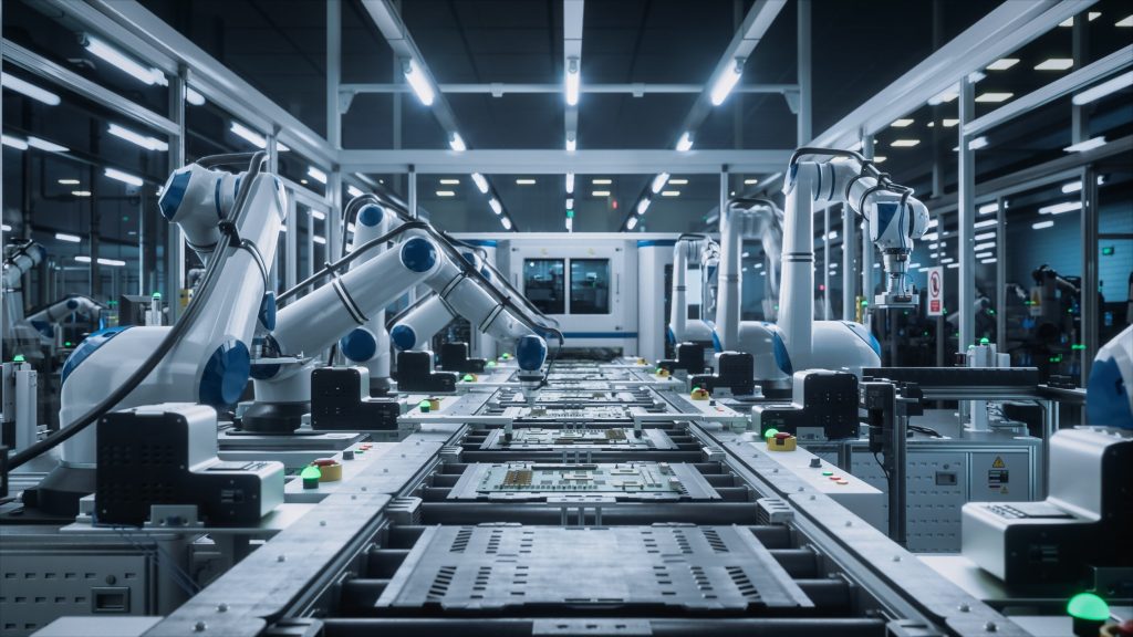 A wide, slightly angled shot of a modern, highly automated factory floor. Multiple white and blue robotic arms extend over a conveyor belt system, where electronic circuit boards are being assembled. The factory is brightly lit with cool white fluorescent lights, reflecting off the clean, metallic surfaces. Green indicator lights are visible on various machines. The overall impression is one of precision, efficiency, and advanced industrial technology.