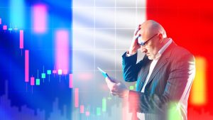 A bald man with glasses, wearing a pinstriped suit, holding his head in distress while looking at a tablet. Behind him, a translucent French flag overlays a digital grid and financial candlestick charts. The charts feature prominent red (pink) downward-trending bars, indicating a market decline, with some smaller green bars visible.